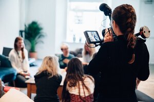 [Translate to English:] Camera crew filming people in conference setting